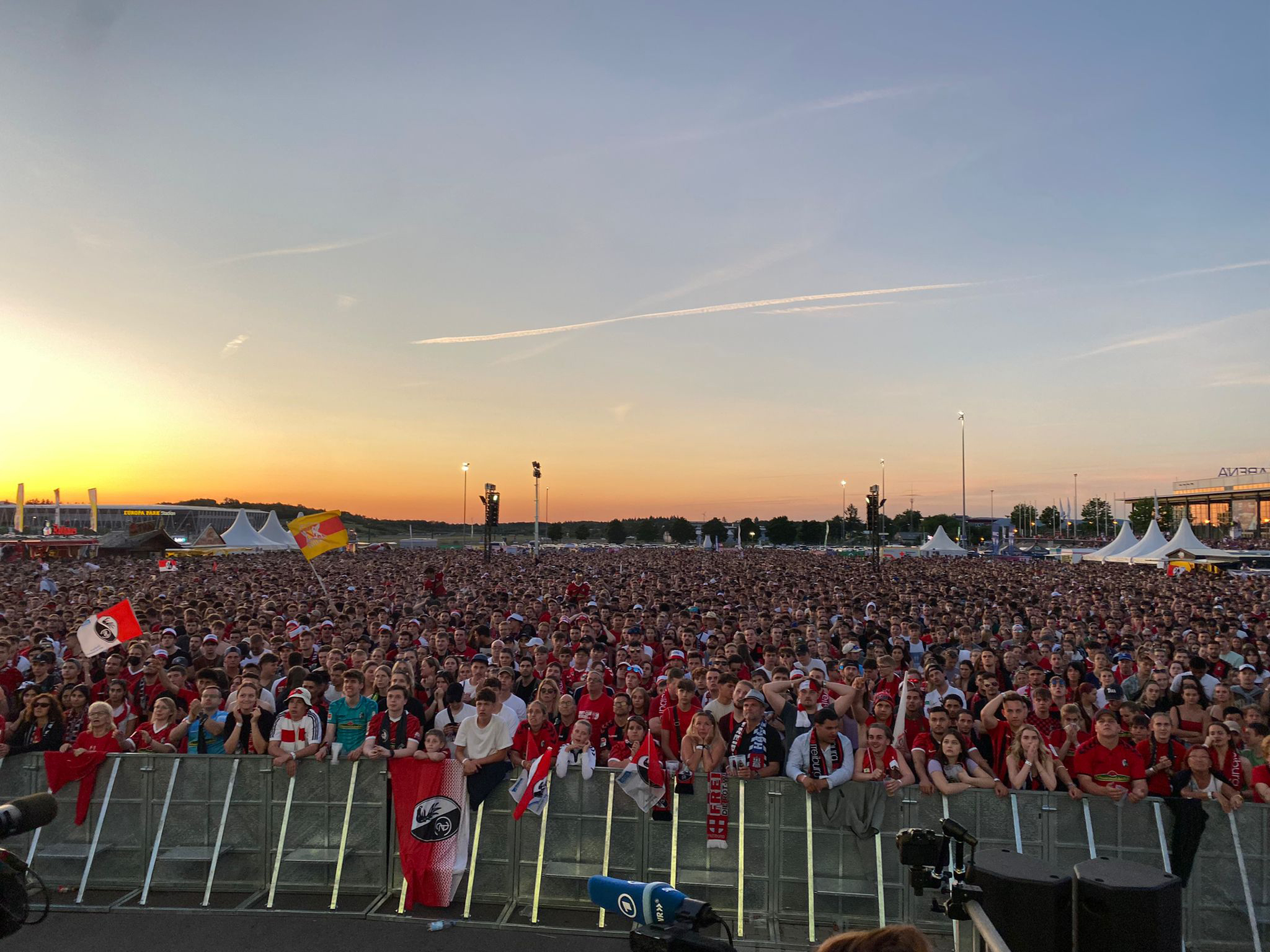 Menschenmengen in Trikots schauen auf Leinwand